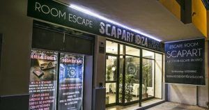 El exterior de Scapart - Escape Room (Ibiza) se transforma por la noche, con carteles luminosos y carteles en las ventanas que atraen a los buscadores de aventuras. - ForTwo - Planes para parejas