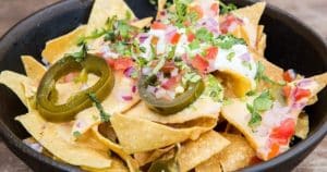 Experimente los vibrantes sabores de Barcelona con un tazón de nachos, cubiertos con jalapeños, tomates cortados en cubitos, cebollas, cilantro y crema agria en Cata de cervezas en BlackLab. - ForTwo - Planes para parejas