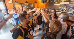 Un grupo brindando alegremente con bebidas en un acogedor bar de Barcelona, saboreando cervezas locales durante la animada Cata de cervezas en BlackLab. - ForTwo - Planes para parejas