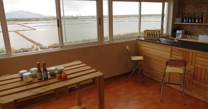Habitación con grandes ventanales con vistas panorámicas a Valencia cuenta con una mesa de madera con condimentos y una barra con taburetes, que recuerda a la Visita a la fábrica de cerveza Gènesis con cata y almuerzo. - ForTwo - Planes para parejas