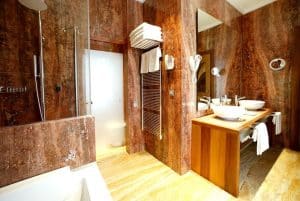 Disfrute del lujo en el Hotel Mirador de Dalt Vila, Ibiza, con su opulento baño con paredes de mármol marrón, lavabos dobles, un tocador de madera y una elegante ducha de cristal. - ForTwo - Planes para parejas
