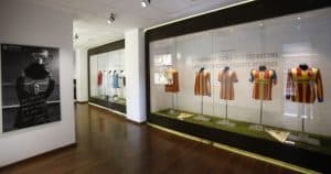 La exposición del museo muestra camisetas de fútbol antiguas en vitrinas a la derecha, con una fotografía en blanco y negro a la izquierda, haciendo eco de la rica historia de Valencia y del Visita Mestalla con el Mestalla Forever Tour (Valencia). - ForTwo - Planes para parejas