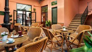 La "Escapada con desayuno y crucero en barco por el Guadalquivir (Sevilla)" ofrece un lugar ideal para desayunar con sillas de mimbre y macetas. Una escalera ofrece vistas a la actividad cercana y al río, con una salida despejada para un acceso cómodo. - ForTwo - Planes para parejas