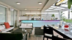 Disfrute de un elegante bar con asientos modernos, una barra con iluminación vibrante y amplios ventanales con vistas a la vegetación. Es perfecto para disfrutar de una "Escapada en el Hotel Neptuno con desayuno y cava (Valencia)". - ForTwo - Planes para parejas
