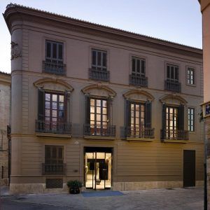 El Hotel Caro, un edificio histórico situado en una tranquila calle de Valencia, cuenta con altas ventanas arqueadas, contraventanas oscuras y balcones ornamentados. - ForTwo - Planes para parejas