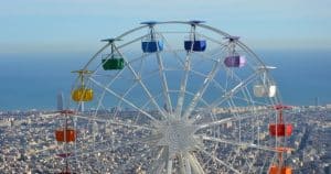 La vibrante noria del Tibidabo ofrece impresionantes vistas de Barcelona y el océano, todo ello bajo un cielo azul claro, con Entradas para el parque de atracciones Tibidabo (Barcelona). - ForTwo - Planes para parejas