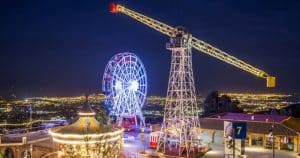 El parque de atracciones iluminado con una noria, una grúa y luces de la ciudad prepara el escenario para las icónicas "Entradas para el parque de atracciones Tibidabo (Barcelona)" del Tibidabo con vistas a la ciudad. - ForTwo - Planes para parejas