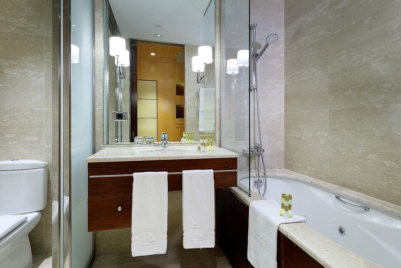 Transforma tu baño en un oasis de modernidad inspirado en el Eurostars Gran Valencia. Disfruta de una elegante bañera, un elegante lavabo con espejo y un inodoro impecable. Detalles como toallas y artículos de aseo cuidadosamente organizados aumentan tu comodidad. - ForTwo - Planes para parejas