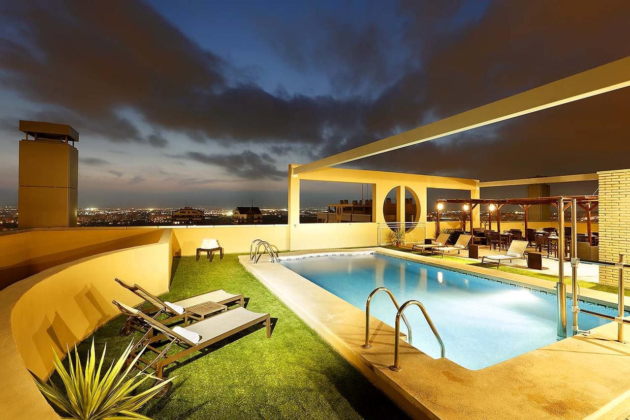 En el Hotel Eurostars Gran Valencia, la piscina de la azotea se transforma en un impresionante escape nocturno con cómodos asientos, césped verde vibrante y cautivadoras luces de la ciudad. - ForTwo - Planes para parejas