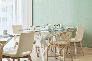 El comedor del Hotel Eurostars Ibiza cuenta con mesas blancas y sillas de mimbre, elegantemente dispuestas para el desayuno con tazas y manteles individuales. - ForTwo - Planes para parejas