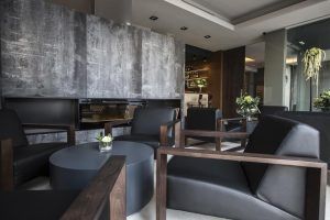 El Hotel Vincci Mercat de Valencia ofrece un moderno salón con sillas de cuero negro, detalles de madera y una elegante mesa de café redonda en un entorno minimalista. - ForTwo - Planes para parejas