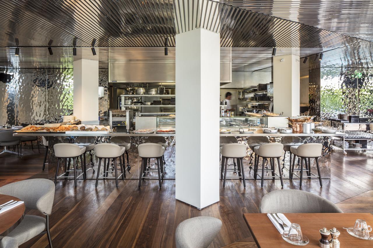 El Hotel Sir Joan en Ibiza cuenta con un moderno interior de restaurante con cocina abierta, elegantes elementos metálicos y suelos de madera. - ForTwo - Planes para parejas