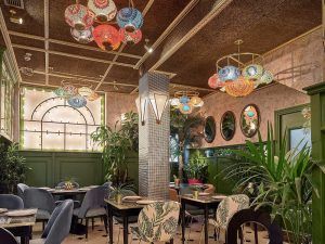 El Restaurante Purnima en Madrid ofrece un ambiente acogedor con luces de colores, paredes verdes, sillas estampadas y exuberante vegetación. Disfrute de los auténticos sabores de la cocina india con su "Menú degustación Indian Cuisine" en esta vibrante delicia para los sentidos. - ForTwo - Planes para parejas