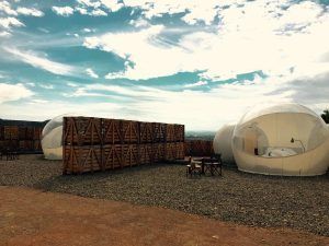 Bajo un cielo nocturno nublado, acogedoras camas en cúpulas de burbujas descansan junto a estructuras de madera que evocan una base lunar. Experimente el Hotel Aire de Bardenas, donde la comodidad terrenal se fusiona con la maravilla celestial. - ForTwo - Planes para parejas