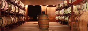 En la bodega El Regajal, poco iluminada y cerca de Madrid, filas de barriles de madera rodean uno central prominente, ideal para una Cata de vino en la bodega El Regajal íntima. - ForTwo - Planes para parejas