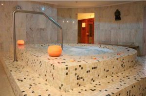 El Circuito termal de spa - Tratamiento deluxe (Tenerife) cuenta con un jacuzzi interior de azulejos con luces de borde ámbar, paredes de mármol y un ambiente similar a un spa, proporcionando una experiencia de retiro serena y lujosa. - ForTwo - Planes para parejas