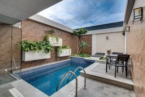 La íntima zona de piscina al aire libre del Zouk Hotel (Madrid) cuenta con exuberantes plantas, tumbonas y una mesa dispuesta bajo un cielo nublado, perfecta para escapadas en pareja. - ForTwo - Planes para parejas