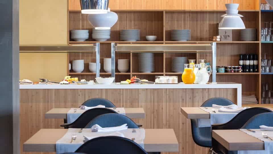 Experiencia Kaitai en Tunateca Balfegó en Barcelona es un moderno restaurante con mesas bien dispuestas, estantes organizados para platos y una barra de desayuno que ofrece jugos y pasteles. - ForTwo - Planes para parejas