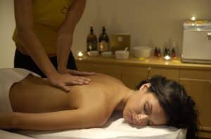 En una habitación poco iluminada de Tenerife, se logra tranquilidad durante la experiencia del circuito termal de spa con masaje, té, chocolate y fruta, mientras los huéspedes disfrutan de un relajante masaje de espalda rodeados de velas y aceites esenciales. - ForTwo - Planes para parejas