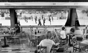 La gente en un acogedor restaurante, con estilo de iglú, disfruta de patinaje sobre hielo para dos en Igloo (Granada) mientras ven un emocionante partido de hockey sobre hielo a través de una gran ventana. - ForTwo - Planes para parejas