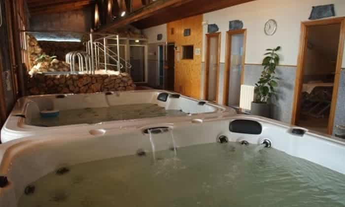 La sala de spa interior de Guadix, llamada "Un circuito de spa perfecto en Guadix (Granada)", ofrece una escapada serena con jacuzzis, paredes revestidas de madera y una escalera a otra zona, que recuerda la atmósfera relajante de Granada. - ForTwo - Planes para parejas