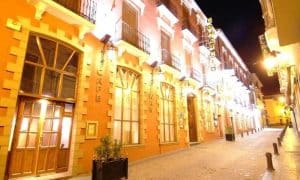 Bajo las luces nocturnas de una calle adoquinada, "Un circuito de spa perfecto en Guadix (Granada)" destaca con su arquitectura decorativa, ofreciendo un vistazo al rico patrimonio de Granada. - ForTwo - Planes para parejas