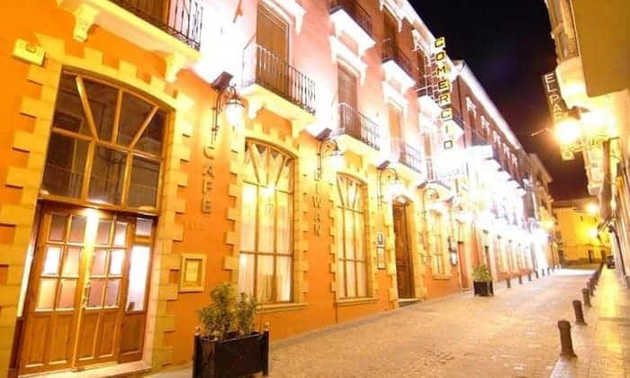 Bajo las luces nocturnas de una calle adoquinada, "Un circuito de spa perfecto en Guadix (Granada)" destaca con su arquitectura decorativa, ofreciendo un vistazo al rico patrimonio de Granada. - ForTwo - Planes para parejas