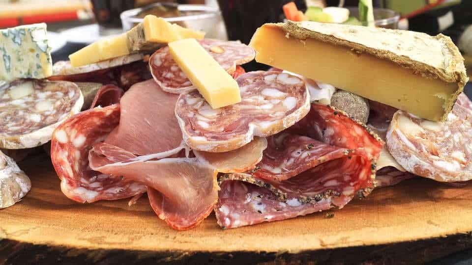 Una tabla de madera de Casa Don Fernando con surtido de embutidos y quesos, ofreciendo una muestra de las delicias culinarias de Cáceres con el paquete Escapada Hotel Soho Boutique que incluye desayuno, degustación de ibéricos y vino. - ForTwo - Planes para parejas