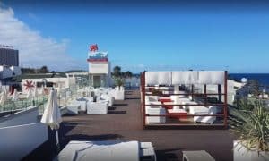 Ubicado en lo alto del Hotel Gala, este salón en la azotea de Tenerife con asientos blancos y sombrillas ofrece impresionantes vistas al océano bajo un cielo azul claro: el refugio perfecto para una "Sesión de spa en pareja en el Hotel Gala (Tenerife). - ForTwo - Planes para parejas