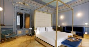 Lujosa suite Preciosa en el Hotel Axel - Solo adultos (Madrid), con cama con dosel, sofisticadas paredes azules y bandeja de desayuno con zumo de naranja en la cama. - ForTwo - Planes para parejas
