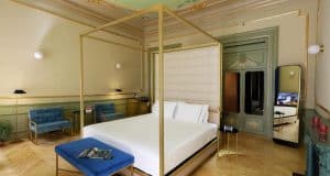 La suite Preciosa del Hotel Axel de Madrid cuenta con una cama con dosel, sillas azules y molduras de techo ornamentadas, diseñadas exclusivamente para adultos. - ForTwo - Planes para parejas