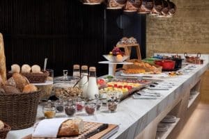 Deléitese con un elegante buffet con una variedad de panes, quesos, frutas y cereales en una encimera de mármol en la prestigiosa Suite Presidencial de Meliá Castilla en Madrid. - ForTwo - Planes para parejas