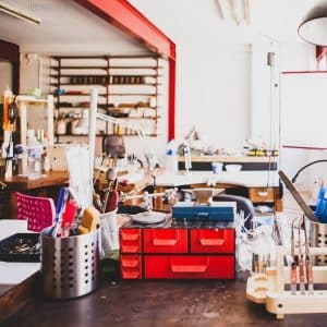 Un espacio de trabajo bien organizado con cajones rojos, herramientas y estantes en una habitación bien iluminada invita a disfrutar de la Experiencia Joyero por un día (Barcelona). - ForTwo - Planes para parejas