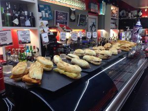 En la barra de un bar de Bilbao, el "Combinado de mojitos y pintxos únicos" deleita con su variedad de pintxos en bandejas de pizarra y mojitos perfectamente elaborados entre una selección de botellas. - ForTwo - Planes para parejas