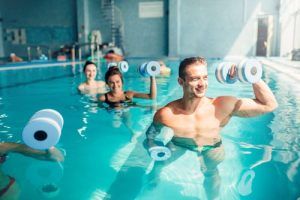En Bilbao, la gente disfruta del aquagym con mancuernas de espuma en una piscina, sonriendo ante las encantadoras instalaciones. Tras una sesión revitalizante, se relajan durante 90 minutos en el exclusivo Circuito Termal y disfrutan de la tranquilidad de un jardín privado. - ForTwo - Planes para parejas