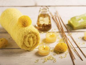 Una escena de spa con una toalla amarilla enrollada, velas, barritas de incienso, un tarro de aceite y flores amarillas sobre madera evoca la tranquilidad del Circuito termal 90 minutos + jardín privado (Bilbao). - ForTwo - Planes para parejas