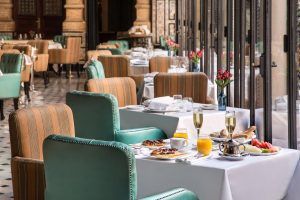 Experimente la máxima elegancia en la Suite Deluxe del Hotel Alfonso XIII en Sevilla, donde el interior del restaurante presume de mesas preparadas, sillas tapizadas y amplios ventanales con impresionantes vistas. Disfrute de un elegante desayuno con bebidas y bollería. - ForTwo - Planes para parejas