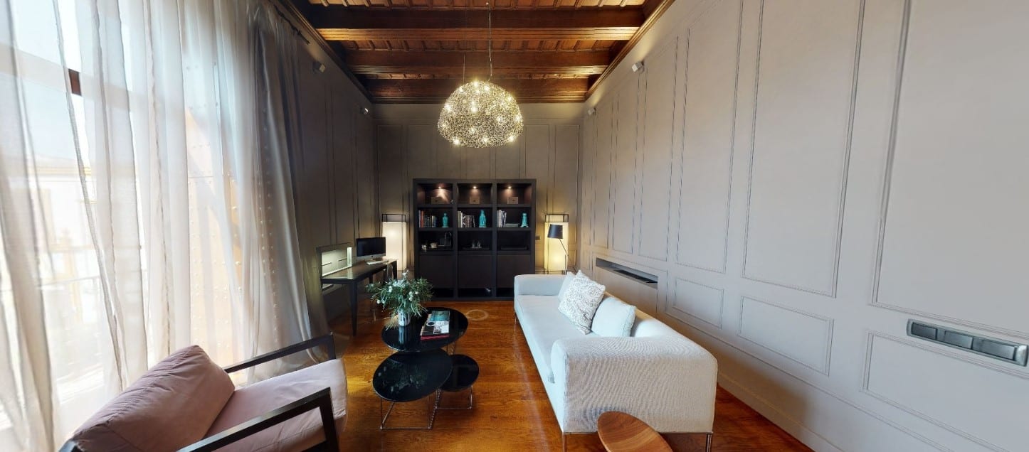 Cree una sala de estar refinada inspirada en las Suites únicas del Hotel Palacio De Villapanés en Sevilla, con un sofá blanco, un sillón, una mesa redonda, una lámpara de araña y estantes empotrados bajo un encantador techo de madera. - ForTwo - Planes para parejas