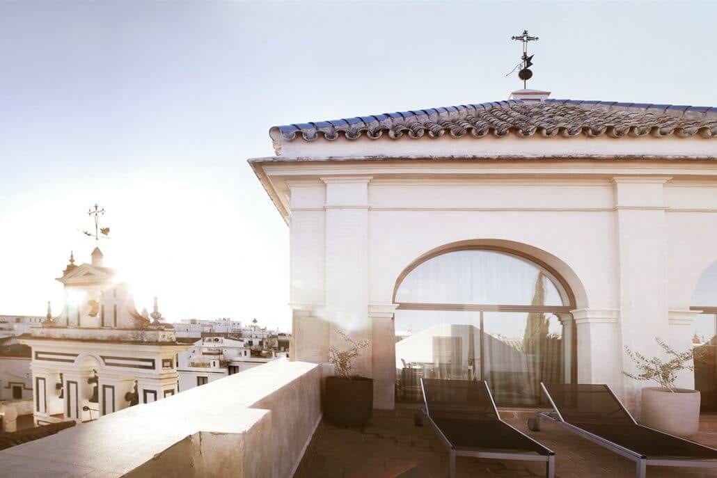 Relájese en la soleada terraza del Hotel Palacio de Villapanés, Sevilla, con tumbonas y vistas a la arquitectura histórica. Disfrute de nuestras Suites Únicas para una estancia inolvidable. - ForTwo - Planes para parejas