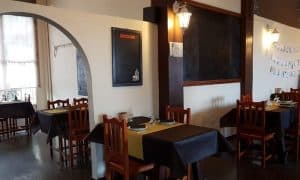 El Menú para dos de La Factoría de Parrilla García en Tenerife ofrece un ambiente acogedor con sillas de madera, un menú en la pizarra y mesas cuidadosamente preparadas con manteles individuales amarillos: una cálida encarnación de la esencia de la isla. - ForTwo - Planes para parejas
