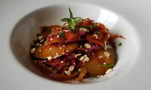 Disfrute de un refrescante comienzo con una colorida ensalada de pepinos, zanahorias y hierbas, con avena en un tazón blanco. Este plato es perfecto para el Menú para dos La Factoría de Parrilla García (Tenerife). - ForTwo - Planes para parejas