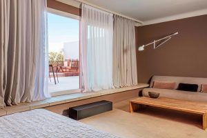 Disfrute de la comodidad de una moderna sala de estar con paredes marrones, un cómodo sofá y una mesa de centro de madera. Las puertas corredizas conducen a un patio exterior, evocando la elegancia de la Suite Grand Terrace, la comodidad hecha habitación en Barcelona. - ForTwo - Planes para parejas