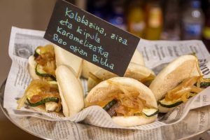 En el Hostel Bcool Bilbao se sirven elegantemente mini bollos bao con cebolla caramelizada y calabacín sobre papel de periódico y con una pequeña pizarra con etiqueta vasca. - ForTwo - Planes para parejas