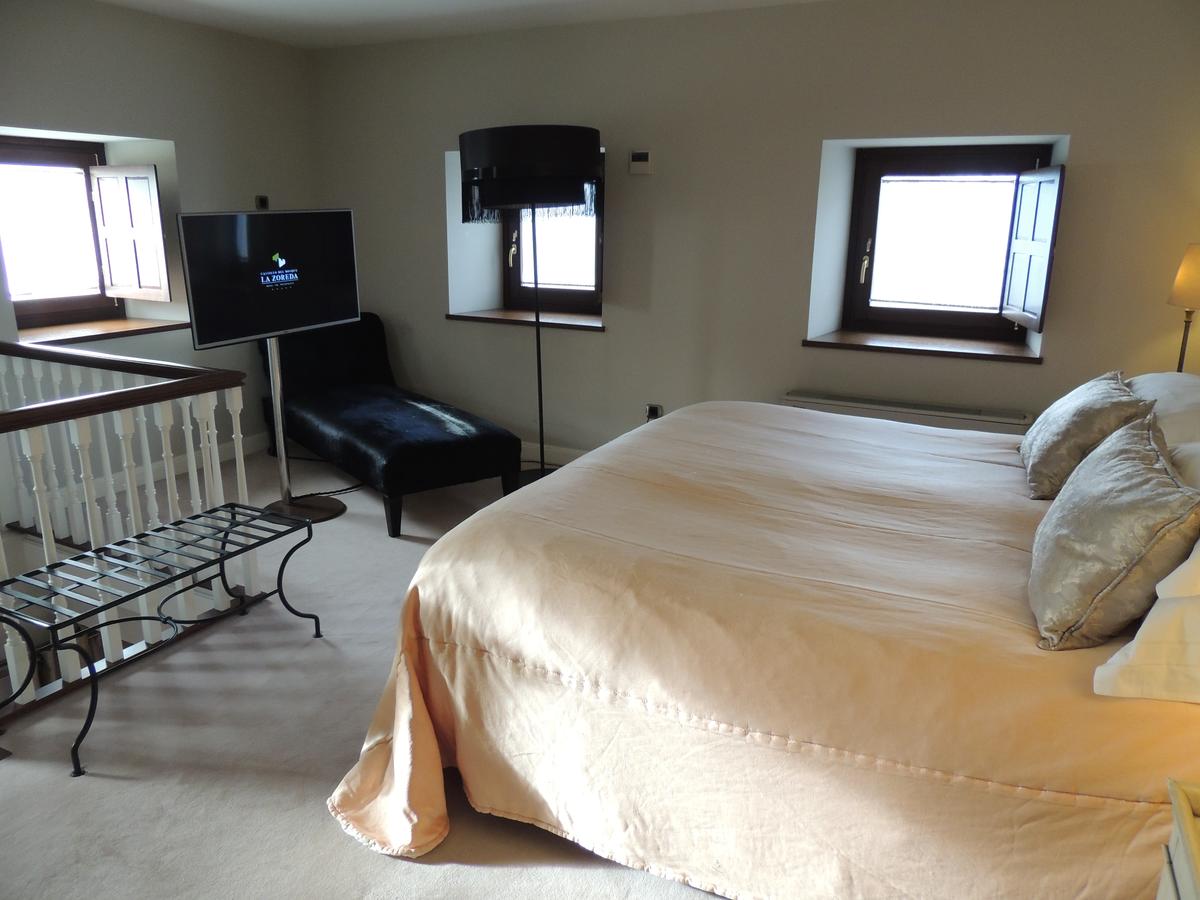 Disfrute de una acogedora y relajante habitación en el Hotel Castillo Del Bosque La Zoreda en Oviedo, equipada con una cama doble, TV, tumbona y dos ventanas con contraventanas en tonos neutros relajantes. - ForTwo - Planes para parejas