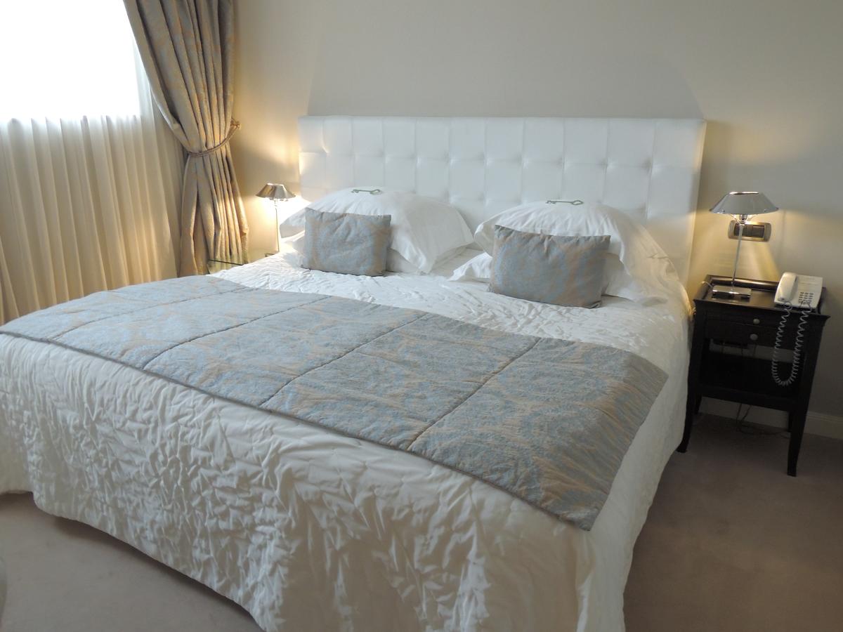 Experimente el lujo en el Hotel Castillo Del Bosque La Zoreda, Oviedo. Disfrute de una elegante habitación con una cama grande con cabecero blanco capitoné, ropa de cama gris y mesitas de noche con lámparas y teléfono. - ForTwo - Planes para parejas