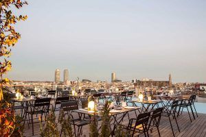 Disfrute de una cena en la azotea al atardecer con vistas al horizonte de Barcelona, con mesas, sillas e iluminación ambiental. Ideal para los huéspedes de la Grand Suite: la joya de la corona del Grand Hotel Central que buscan una velada memorable. - ForTwo - Planes para parejas