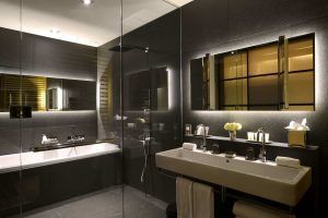 La Grand Suite, la joya de la corona del Grand Hotel Central (Barcelona), cuenta con un moderno baño con un gran lavabo, espejo iluminado, elegantes azulejos oscuros y una lujosa bañera, ideal para relajarse después de explorar las vibrantes calles de la ciudad. - ForTwo - Planes para parejas