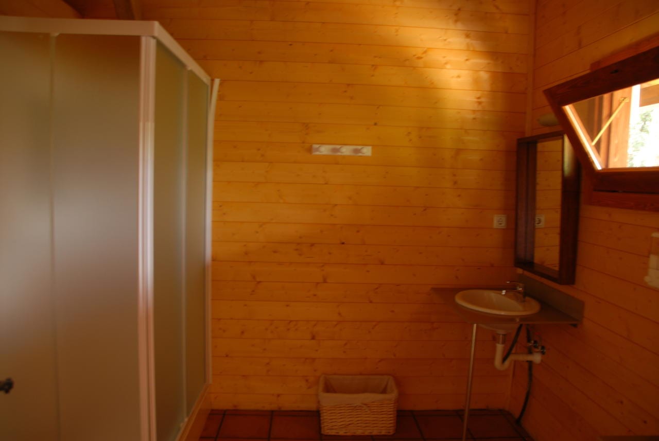 Experimente la magia de la Habitación mágica en los árboles de Cabanes Dosrius (Barcelona), que cuenta con un baño de madera con ducha, lavabo, espejo y una pequeña cesta en el suelo de baldosas, todo ello enclavado entre los tranquilos árboles. - ForTwo - Planes para parejas
