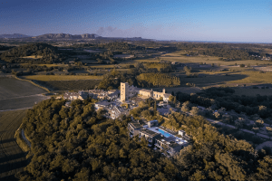 Vista aérea del encantador Hotel Castell d'Emporda (Girona), una finca rural con un majestuoso castillo, una piscina serena y amplios campos bajo un cielo azul brillante. - ForTwo - Planes para parejas