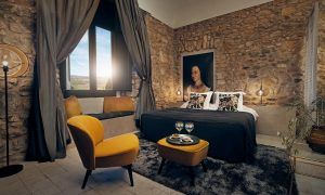 Relájese en una acogedora habitación con paredes de piedra, una cama grande, obras de arte y sillones en el Hotel Castell d'Emporda de Girona. Disfrute de las vistas desde la ventana. - ForTwo - Planes para parejas